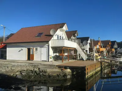 a house on a dock next to a body of water at Fishermen's Cabin With Sea View in Bømlo