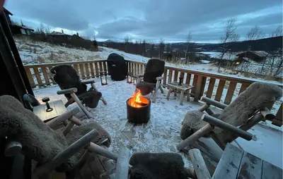 a snow covered porch with chairs and a fire at Amazing Home In Røn With Sauna in Ron