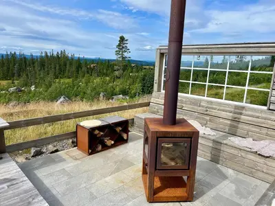 a wood stove sitting on a deck with a view at TexasToppen, cabin in Hafjell with sauna in Hafjell