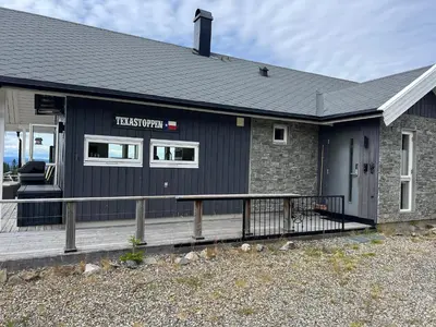 a black house with a porch and a deck at TexasToppen, cabin in Hafjell with sauna in Hafjell