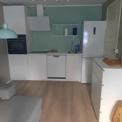 a white kitchen with white appliances and a wooden floor at Liten leilighet in Lii