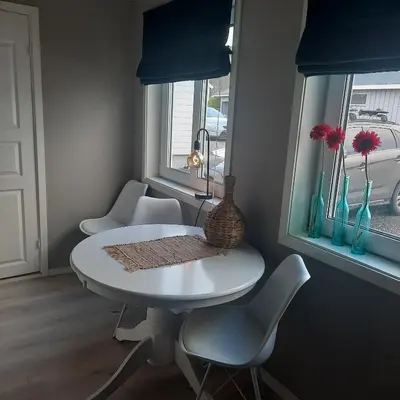 a white table and chairs in a room with windows at Liten leilighet in Lii