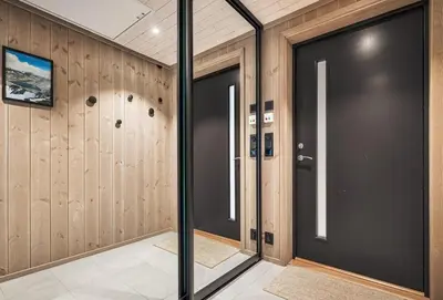 a hallway with two black doors and wooden walls at Exclusive and Uniqe Apartment - Ski in ski out! in Vossevangen