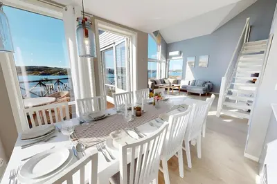 a dining room with a table and chairs with a view of the ocean at Ocean view and jacuzzi in Forland