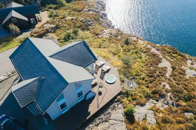 an aerial view of a house on a hill next to the water at Ocean view and jacuzzi in Forland