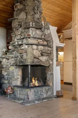 a stone fireplace with a fire in it at Bekkeblom, family cabin with extension in Hafjell in Hafjell