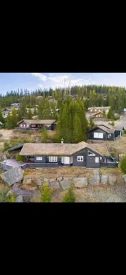 a group of buildings on a hill with trees at Bekkeblom, family cabin with extension in Hafjell in Hafjell