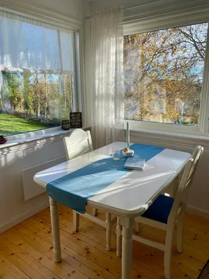 a white table and chairs in a room with two windows at A Cozy Nordic Home in Ålset