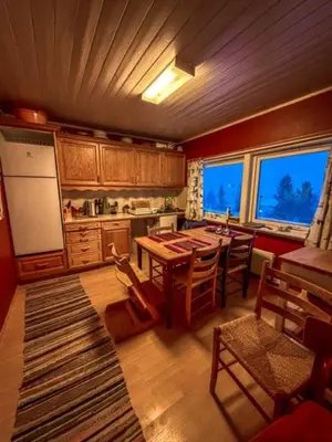 a kitchen with a table and chairs and a refrigerator at Charming Norwegian Cottage in Lyngen