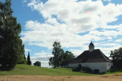 a small white building with a clock tower on a hill at Torshov Gård, Viking grounds in Hamar