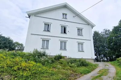 a white house on a hill with a dirt road at Torshov Gård, Viking grounds in Hamar