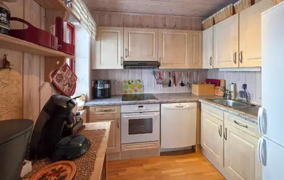 a kitchen with white appliances and wooden cabinets at Amazing Apartment In Edland With House Sea View in Nesland