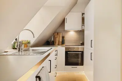 a kitchen with white cabinets and a sink at Modern apartment on Bryggen Walking distance to everything! in Bergen