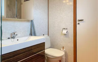 a bathroom with a white sink and a toilet at Nice Home In Harøya With Harbor View in Steinshamn