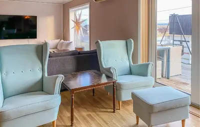 a living room with two chairs and a table and a couch at Nice Home In Harøya With Harbor View in Steinshamn
