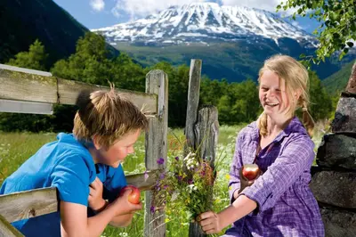 a boy and a girl standing next to a fence with a mountain at Rjukan Hytteby in Rjukan