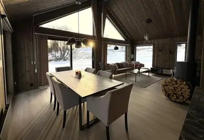 a dining room and living room with a table and chairs at Gemütliche Hütte in traumhafter Natur auf 1000 m in Ål