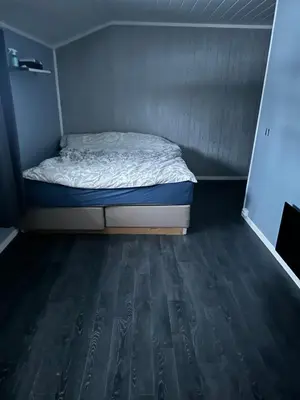 a small bed in a small room with a wooden floor at Bolig sentralt på Røros in Røros