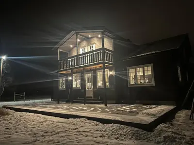 a large wooden building in the snow at night at Bolig sentralt på Røros in Røros
