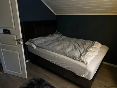 an unmade bed in a corner of a room at Bolig sentralt på Røros in Røros