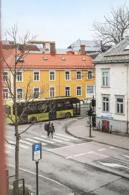 a yellow bus driving down a city street with people at 3FF - Newly renovated studio apt in the middle of the city centre in Trondheim