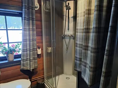 a bathroom with a shower with a toilet and a window at 8 person holiday home in Jordet in Jordet