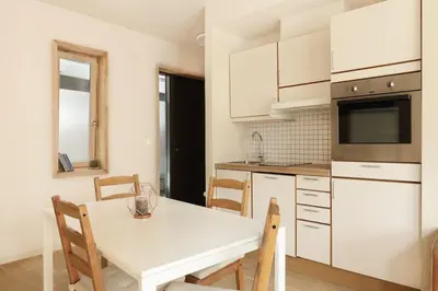 a white kitchen with a white table and chairs at Elegant 1-Bed Apt in City Centre in Trondheim