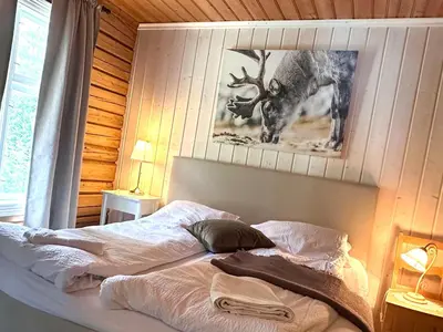 a bed in a bedroom with a picture of a deer at Charming Guesthouse farm in Hølera