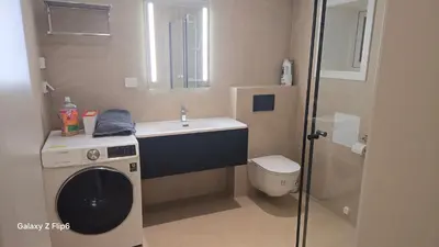 a bathroom with a washing machine and a sink at Apartament Vigra Fjord in Synes