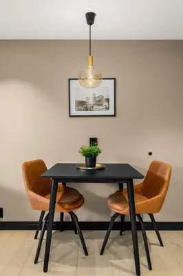 a black dining room table with chairs and a light fixture at Grand Junior Suite in Molde