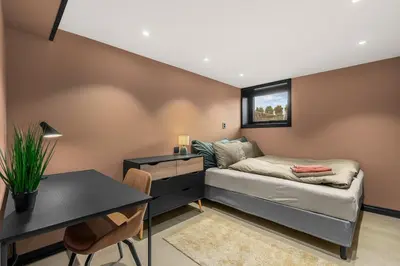 a room with a bed and a desk and a table at Grand Junior Suite in Molde