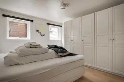 a white bedroom with white cabinets and a bed at 3 soverom, sentralt i Bergen og moderne bad in Bergen