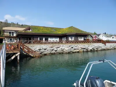 a boat in the water next to a house at 4 person holiday home in Eidsvåg in Eidsvåg