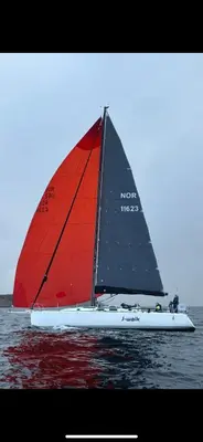 a boat with a red sail on the water at Siggjo Guesthouse Bømlo and Stord in Mosterhamn