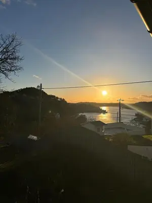 a sunset over a body of water with a fence at Siggjo Guesthouse Bømlo and Stord in Mosterhamn