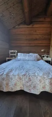 a bedroom with a large bed with wooden walls at Krøderen Laftet tømmerstue fra 2021
