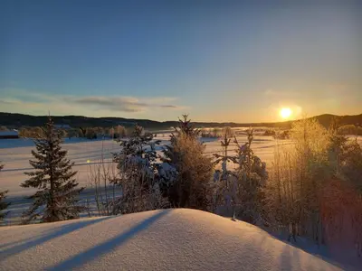 a snow covered field with the sun setting in the distance at Krøderen Laftet tømmerstue fra 2021