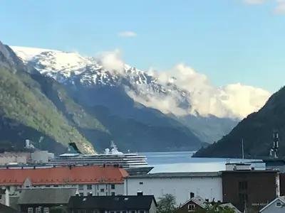 a cruise ship in a body of water with mountains at Near Trolltunga and centre of Odda in Odda
