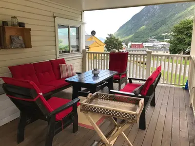 a porch with red chairs and a table on a balcony at Near Trolltunga and centre of Odda in Odda