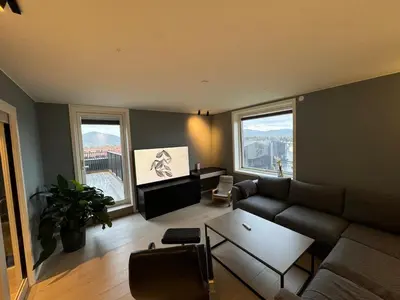 a living room with a couch and a table and two windows at Family-friendly luxury penthhouse with three bedrooms in Stjoerdal