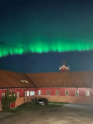 a building with the green northern lights in the sky at Leilighet I låve in Gran