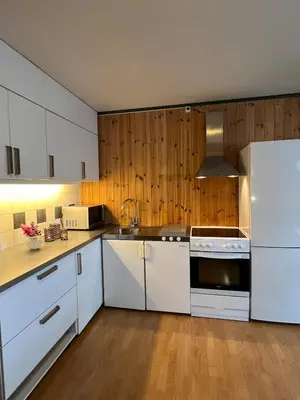 a kitchen with white cabinets and a white refrigerator at Leilighet I låve in Gran