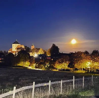 a fence in a field at night with the moon at Leilighet I låve in Gran