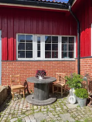 a patio with a table and chairs in front of a building at Leilighet I låve in Gran