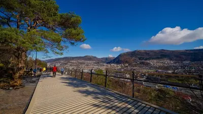 a person walking down a sidewalk with a view of a city at Cozy 2-bedroom apartment near Bergen City Centre in Bergen