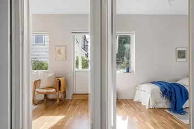 a bedroom with white walls and a bed and windows at Cozy 2-bedroom apartment near Bergen City Centre in Bergen