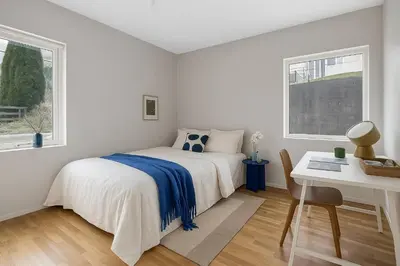 a bedroom with a bed and a desk and two windows at Cozy 2-bedroom apartment near Bergen City Centre in Bergen