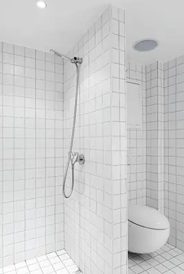 a white tiled bathroom with a toilet and a shower at Studio apartment in city center in Bergen