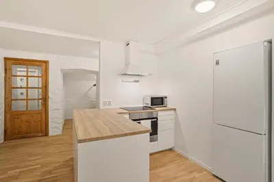 a white kitchen with a counter top and a refrigerator at Bergen city center Kalfaveien in Bergen