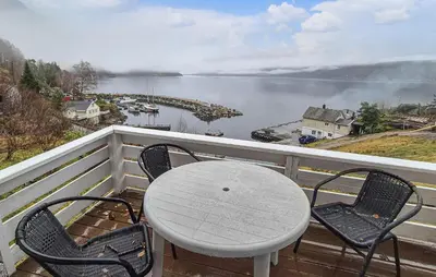 a table and chairs on a balcony with a view of a lake at Nice Home In Vallavik With Wifi in Kaland